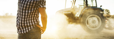 Man and tractor kicking up dust on farm