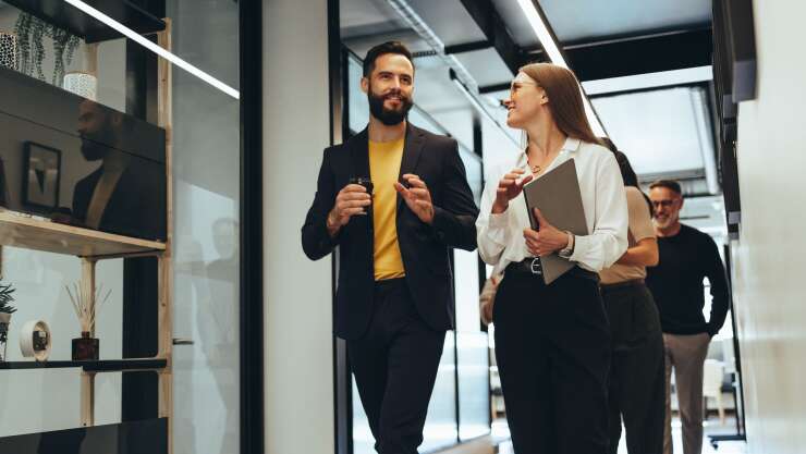 employees-coworkers-chatting-in-office-hallway