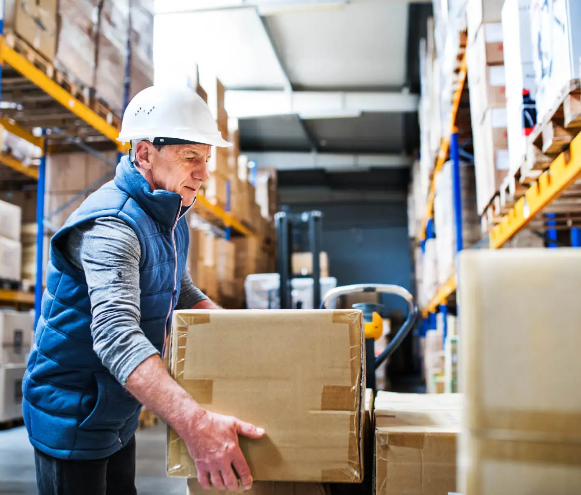 older worker moving boxes at the factory