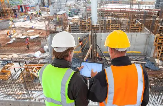 managers overlooking active construction site and discussing plans