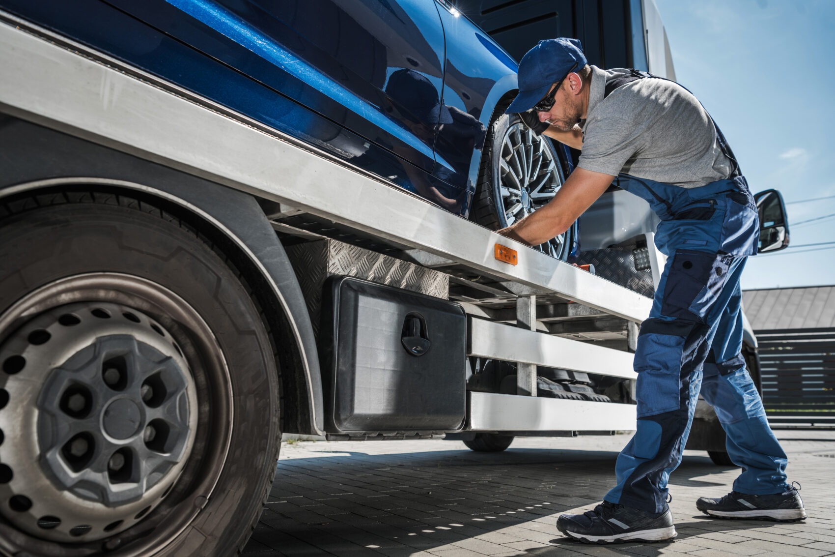 Tow truck operator securing a vehicle on a flatbed, highlighting transportation workplace risk