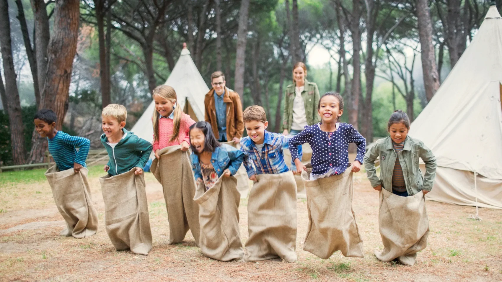 Children participating in a sack race at summer camp, illustrating recreational activities and risks covered by camp insurance.