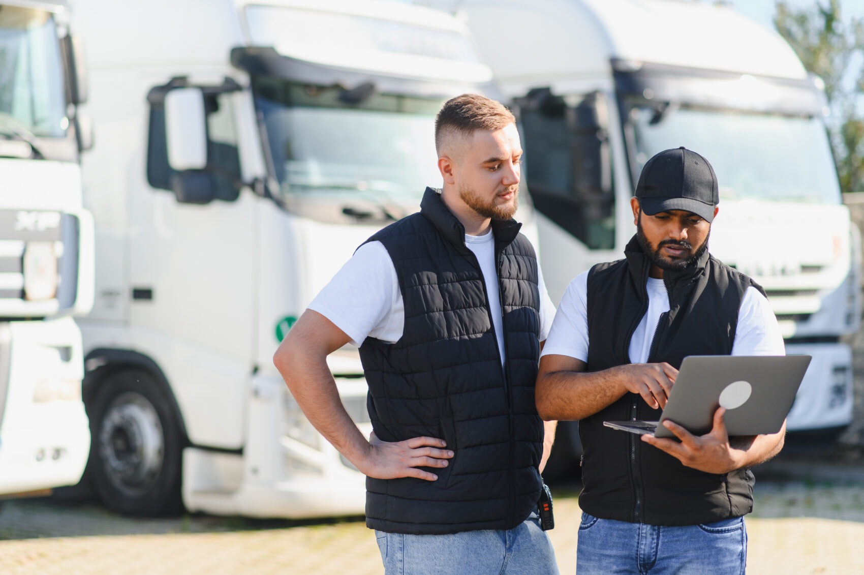 Two truck drivers reviewing fleet management data on a laptop — commercial auto insurance guidance from Marshall+Sterling