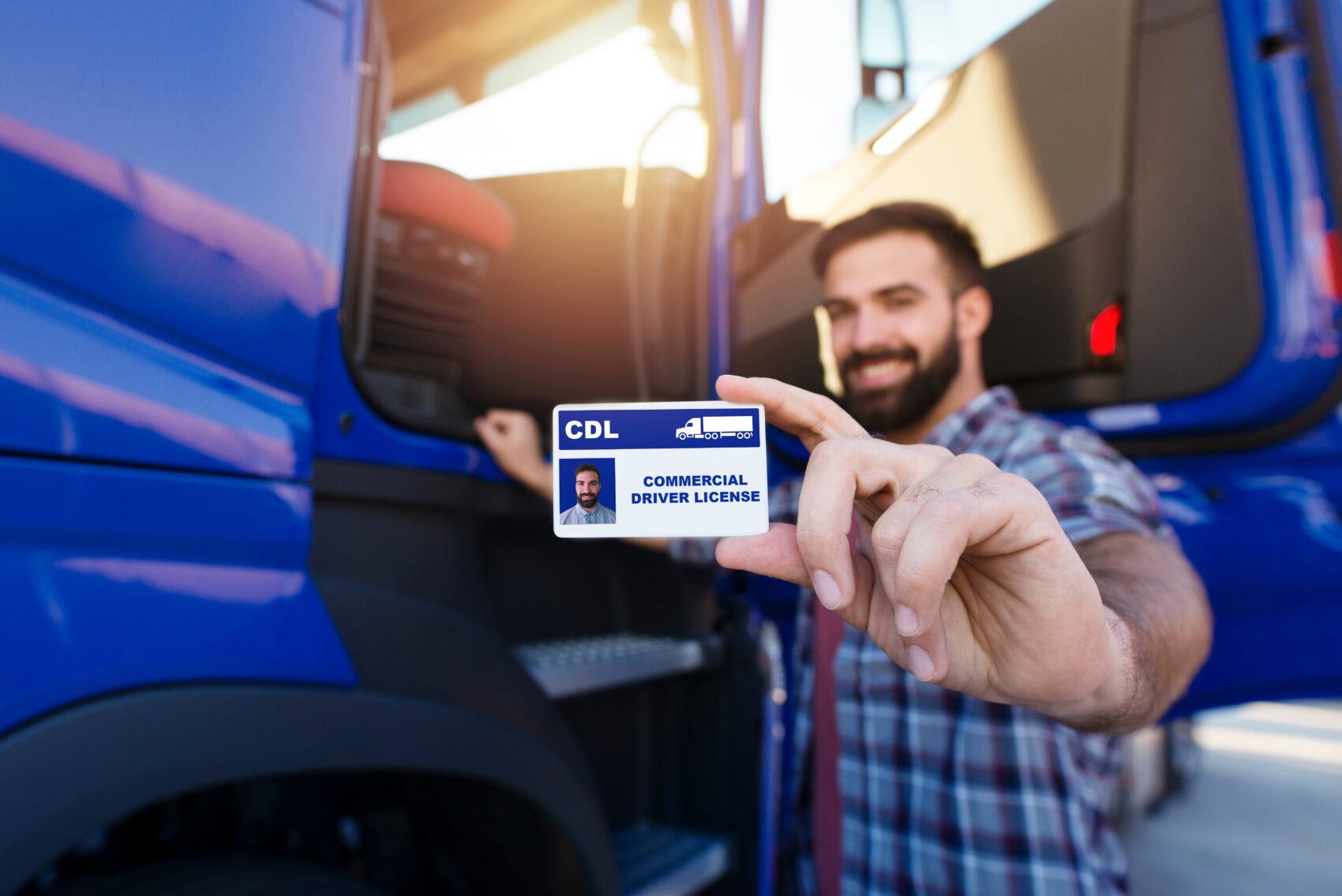 Commercial truck driver holding CDL license in front of his truck — driver qualification requirements and insurance implications for fleet operators