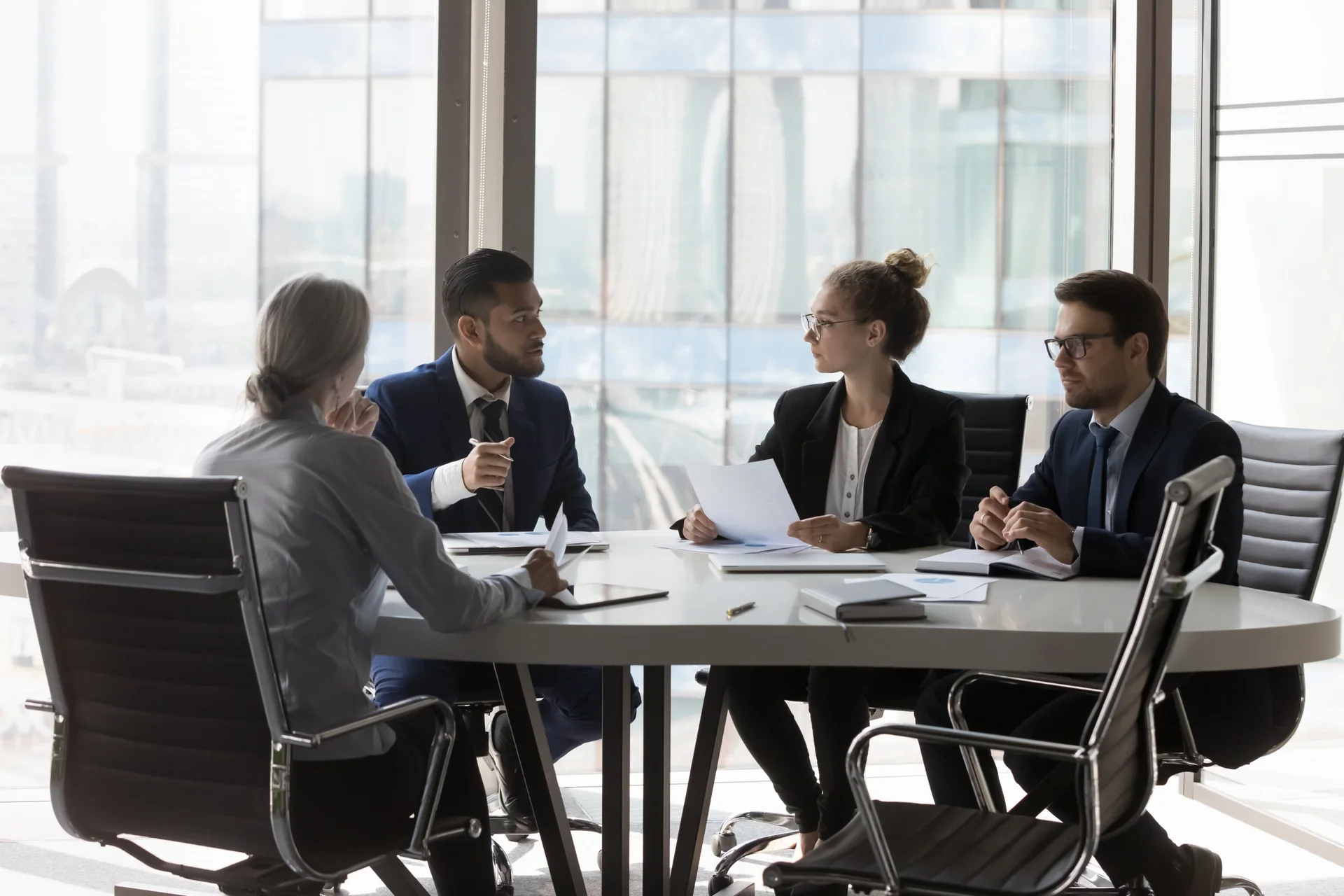 Four people reviewing documents around a conference table
