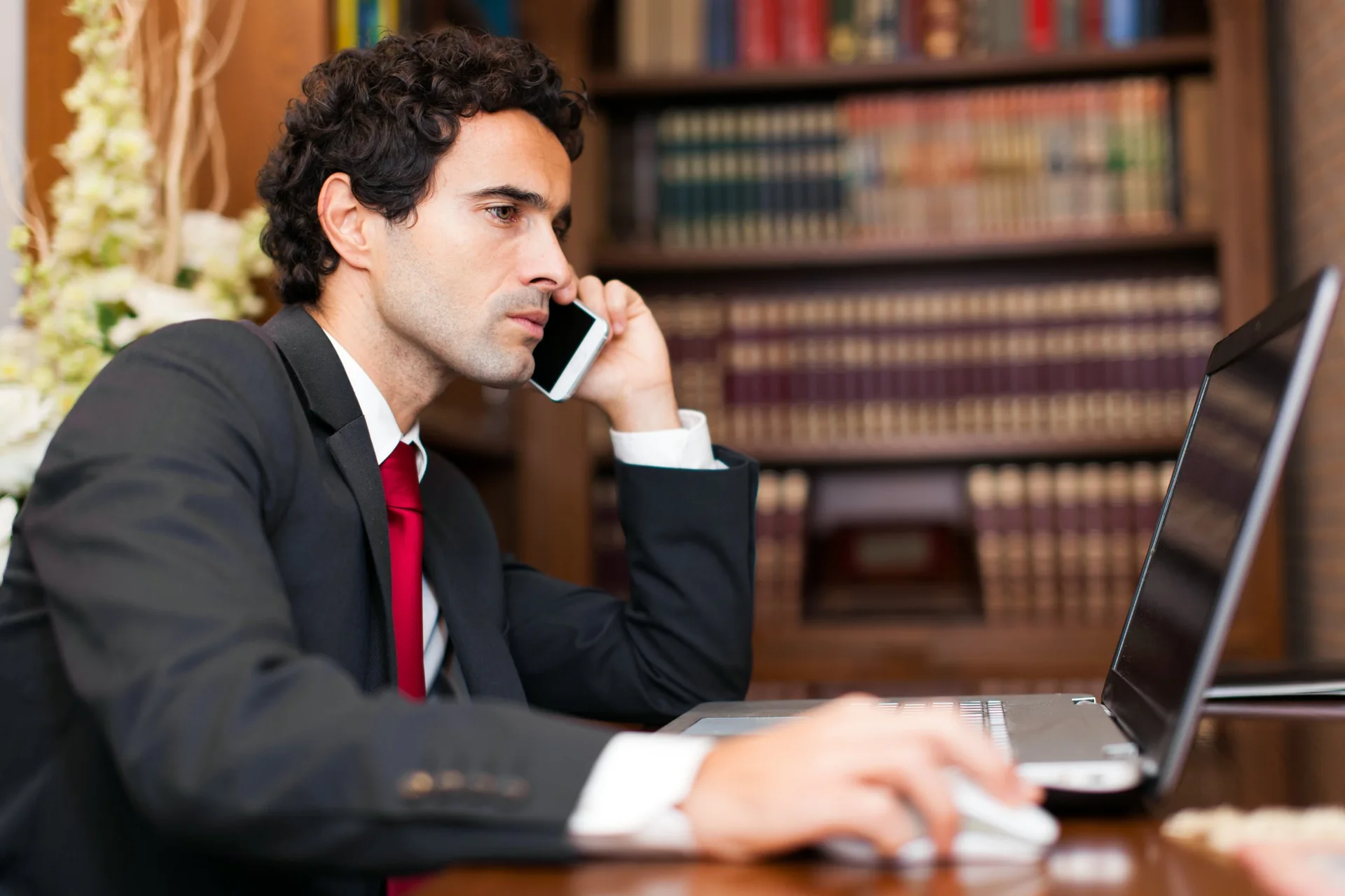 Person speaking on a phone beside an open laptop