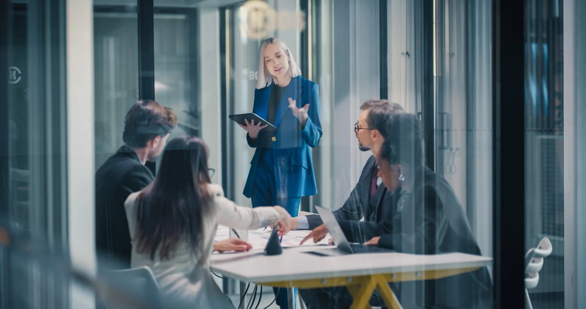 Presenter addressing colleagues in a glass-walled meeting room